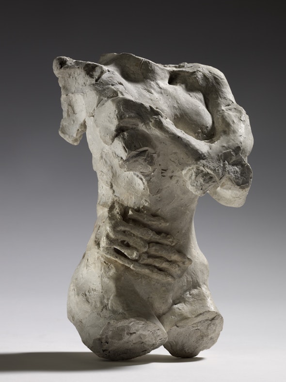 A plaster sculpture of a female torso with a skeleton hand resting on her stomach.