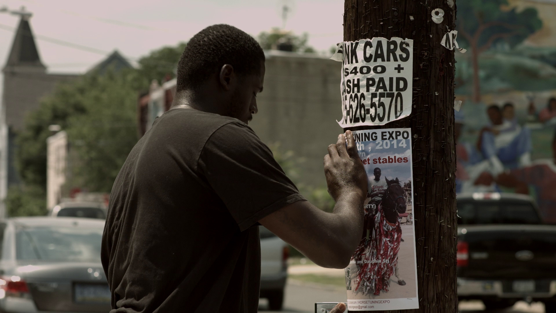A rider pins a poster for the Horse Day event to a utility pole.