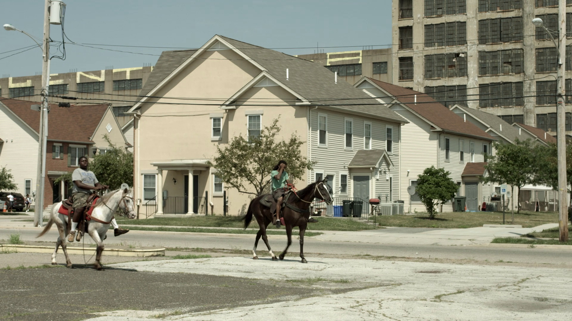Two men ride horses through a poor area of the city.