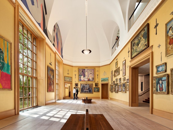 A bright gallery inside the Barnes Foundation is hung with salon-style displays of paintings.