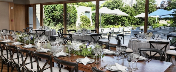 In the Garden Pavilion, tables set with china and wine glasses overlook a garden.