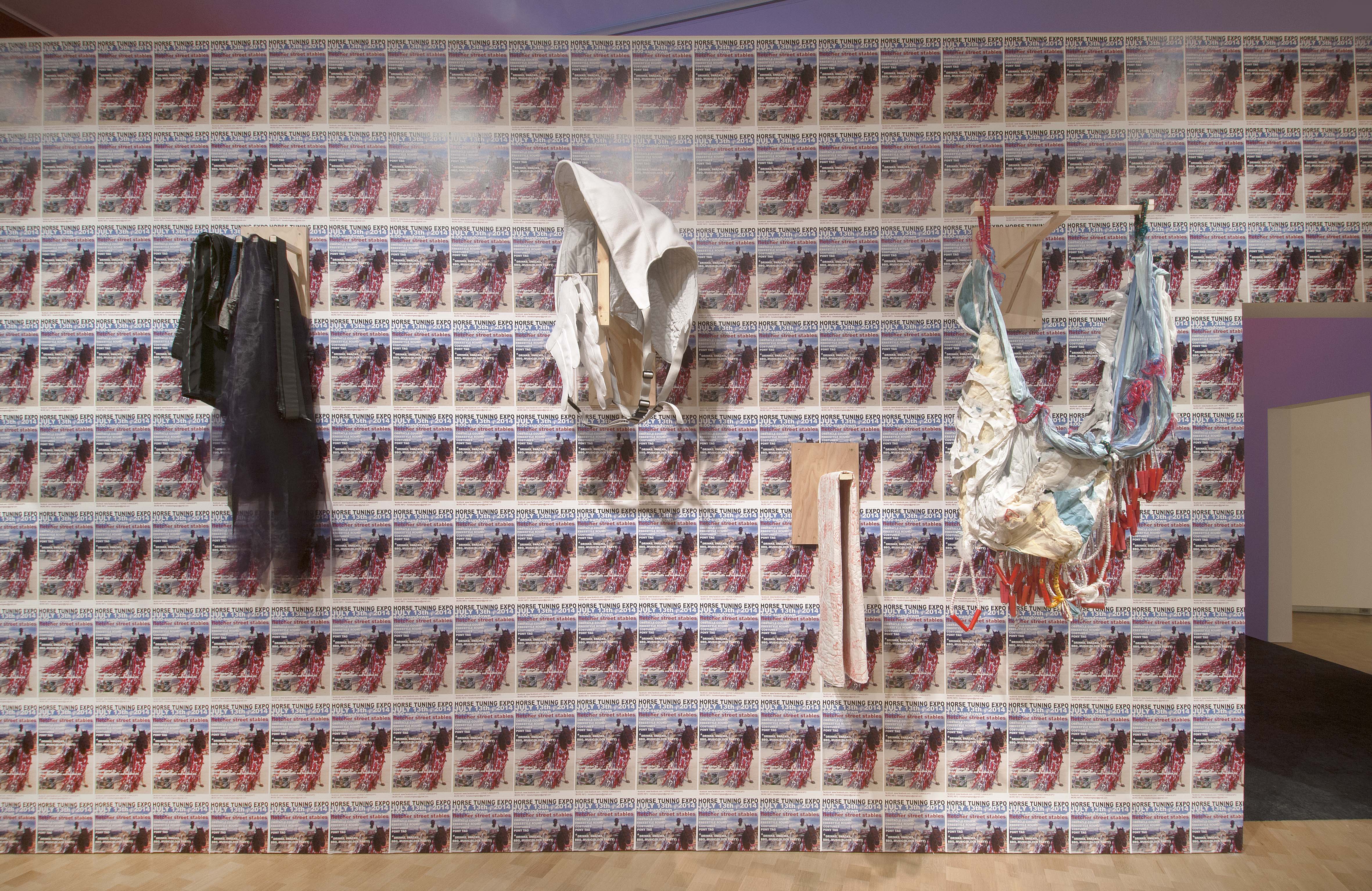 Four of the costumes from Horse Day hang on a wall in the exhibition.