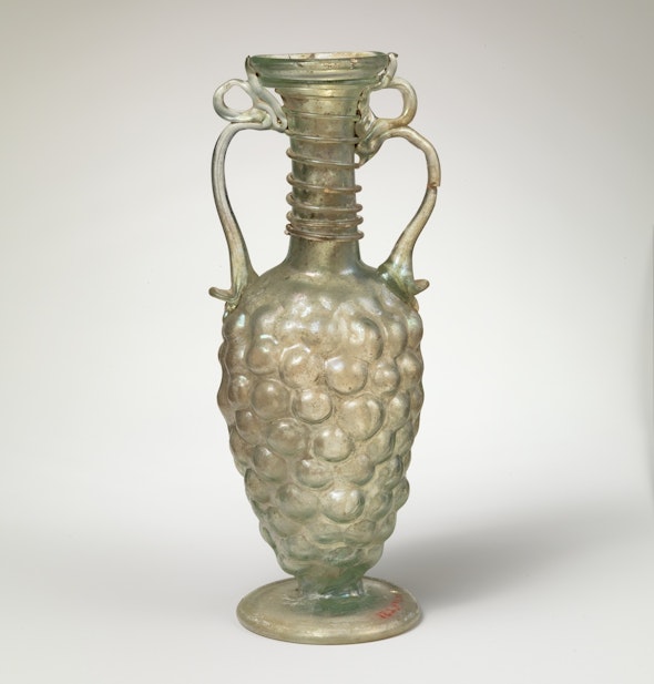 <p>This Roman glass bottle was blown into a mold to mimic grapes.</p>