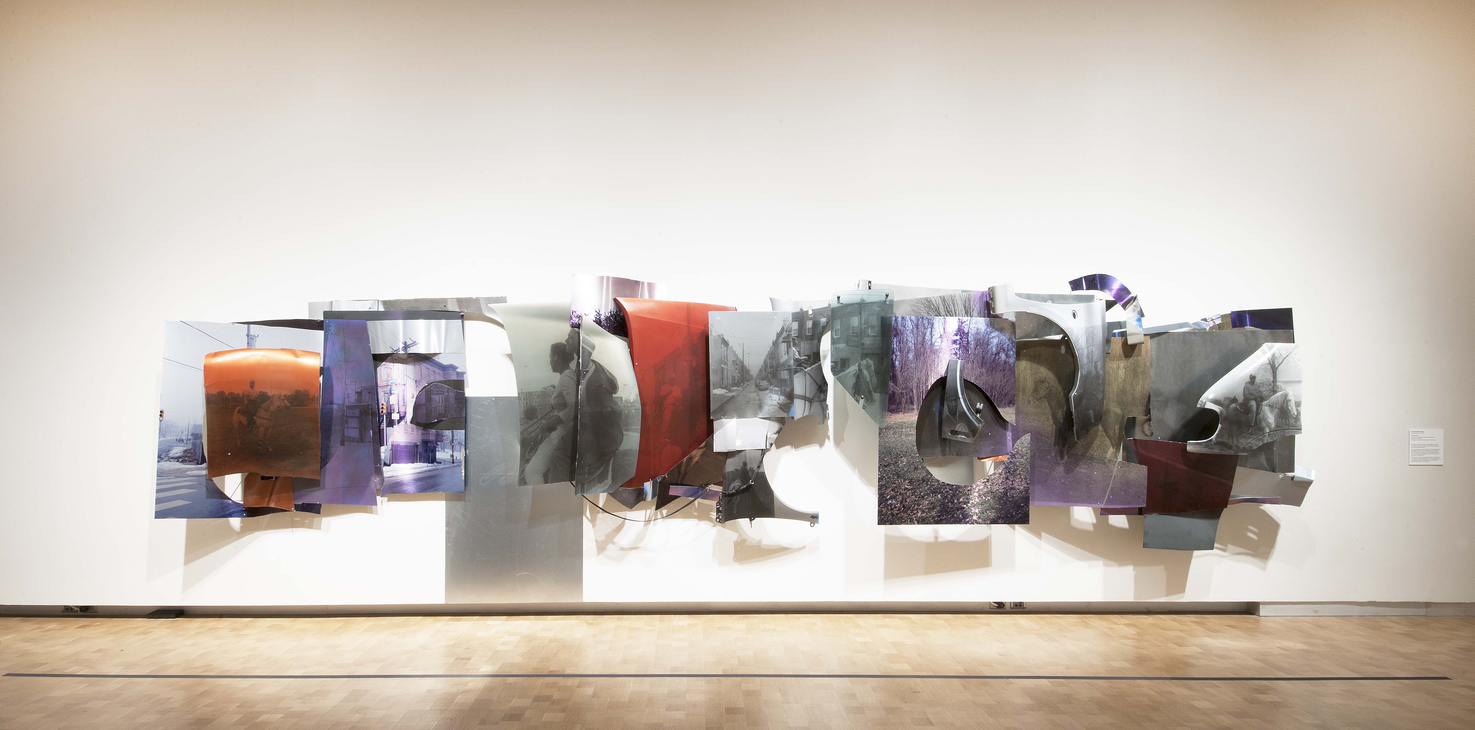 A long construction of metal car parts printed with images from Horse Day is hung in the exhibition.